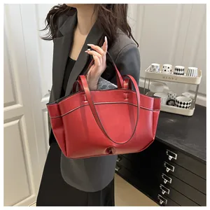 Detail view of red leather tote bag with black edge finish and dual shoulder straps