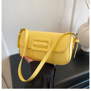 Detail view of the bright yellow faux leather shoulder bag with a large square buckle accent