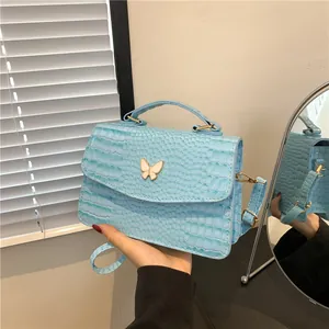Light blue faux crocodile skin bag with a white butterfly buckle and top handle strap