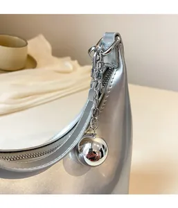 Détail du sac croissant argenté avec fermeture éclair et pendentif boule chromé