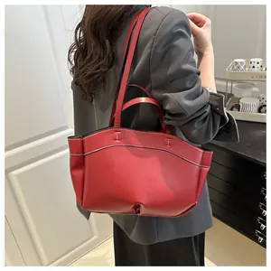 Close-up of dark red leather tote bag showing white contrast stitching and dual straps