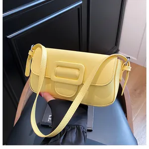 Detail of yellow leather baguette bag with square buckle on dark chair backdrop