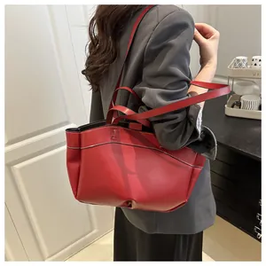 Macro detail of red leather tote bag showing white contrast stitching and matte texture