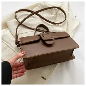 Detail of vintage brown crossbody bag with square buckle and matte leather texture