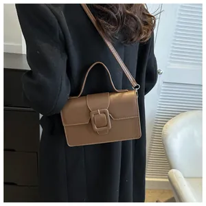 Close-up of brown vintage leather handbag with large square buckle and shoulder strap