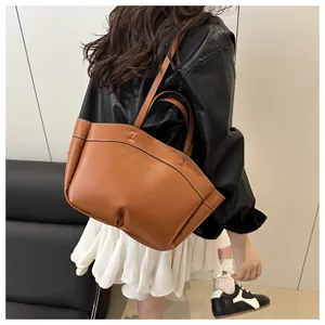 Detail view of brown leather tote bag with white contrast stitching on shoulder