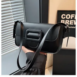 Close-up of black leather baguette bag with a stylish oversized square buckle detail