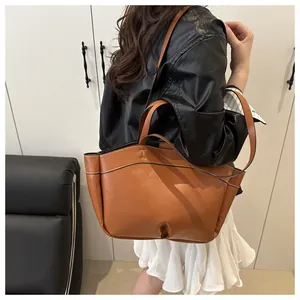 Detail of brown leather tote bag with contrast stitching and versatile shoulder straps