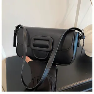Detail of a vintage black rectangular shoulder bag with a large matte buckle and slim strap
