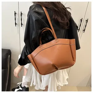 Detail of brown leather tote bag with metallic buckle shown in a stylish back view
