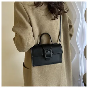 Detail of classic black tote bag with large square buckle and adjustable leather strap