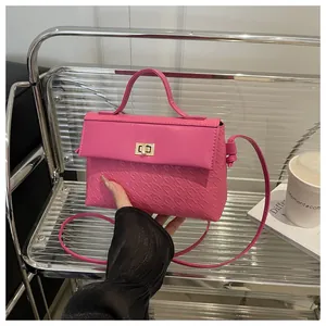 Detail of vibrant pink Kelly bag with gold metal twist lock and geometric embossing
