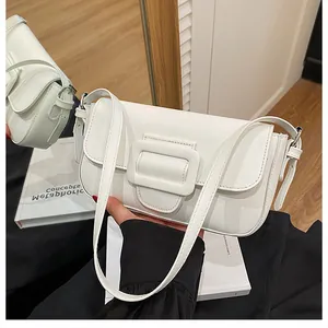 Detail of white minimalist baguette bag featuring a large leather square buckle decoration