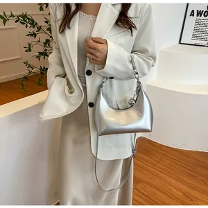 Sac hobo argenté moderne porté à l'épaule par un mannequin vêtu d'un tailleur chic