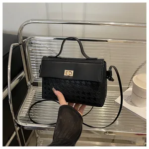 Detail of black Kelly bag with houndstooth texture and golden twist lock closure