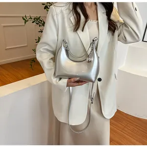 Détail du sac croissant argenté avec finition métallique brillante et charm boule en métal