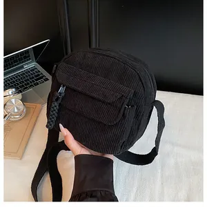 Close-up of black corduroy crossbody bag with flap pocket and textured woven zipper detail