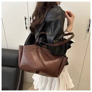 Detail of brown leather tote bag with white contrast stitching and I-shaped cutout design