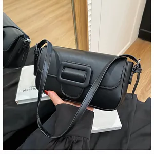 Detail shot of a black rectangular shoulder bag featuring a large decorative matte buckle