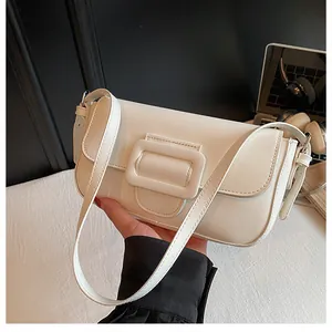 Detail of minimalist cream beige baguette bag featuring sleek faux leather and silver metal buckles
