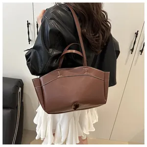 Brown leather tote bag featuring contrast white stitching and 3D folding side details