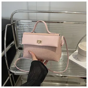 Pink Kelly bag with houndstooth texture and gold clasp shown in a lifestyle setting