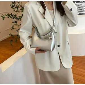 Détail du sac hobo argenté avec pendentif sphérique et logo embossé élégant