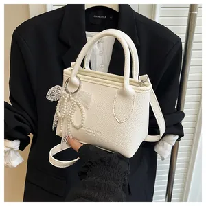Detail of white litchi leather bag with pearl bow charm and Fashion Bags logo