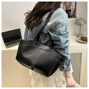 Detail of a large black tote bag featuring distinctive white contrast stitching and shiny leather
