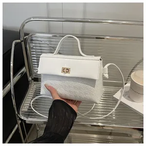 Detail of white Kelly bag featuring houndstooth texture and golden twist lock closure
