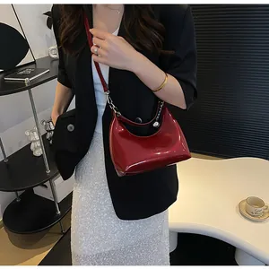 Détail du sac bandoulière en cuir verni rouge avec chaîne argentée et zip