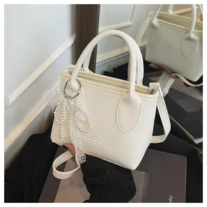 Macro shot of white pebble grain leather mini tote with pearl bow and logo detail