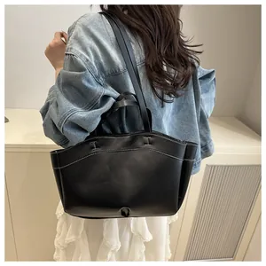 Detail showing back view of black tote bag with white contrast stitching and long shoulder strap