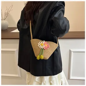 Detail of woven straw crossbody bag with floral accents and a pearl button closure