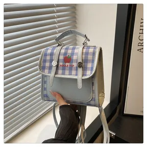 Detail of light blue plaid backpack featuring apple embroidery and silver metal hardware