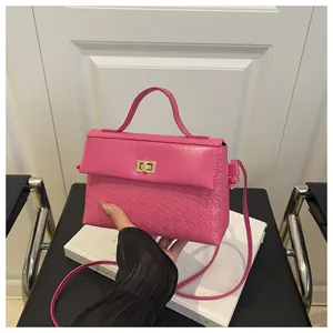 Macro detail of rose pink Kelly bag showing embossed texture and gold twist lock closure