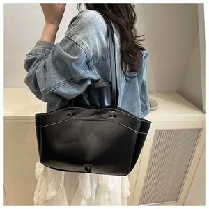 Detailed view of black leather tote bag featuring contrast white stitching and shoulder straps