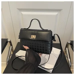 Close-up of contrast kelly bag featuring houndstooth texture and golden twist lock
