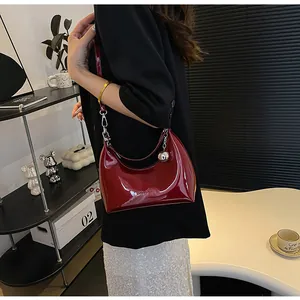 Détail du sac hobo bordeaux brillant avec ferrures argentées et pendentif boule métallique