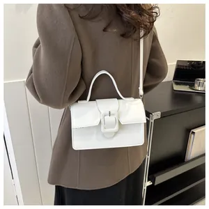 Lifestyle shot of white glossy leather handbag with bold buckle detail worn on shoulder