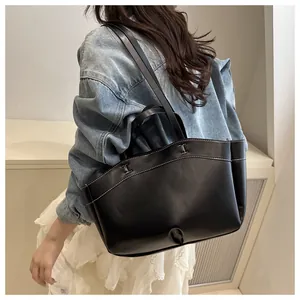 Detail of black leather tote bag featuring contrast stitching and H-shaped design on the front
