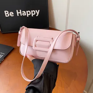 Pink rectangular leather shoulder bag with decorative square buckle in a lifestyle setting
