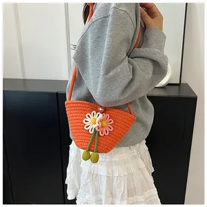 Detail view of bright orange woven crossbody bag with 3D flowers and pearl button