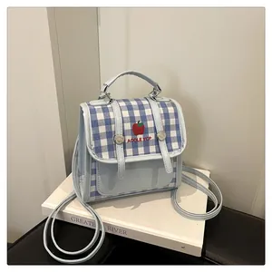 Detail view of light blue checkered mini backpack with apple print and silver buckles