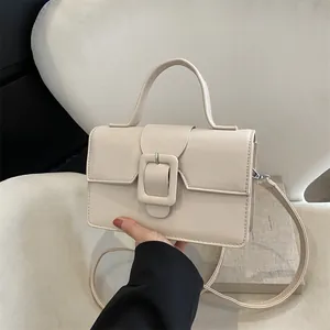 Minimalist beige leather handbag with square buckle and adjustable strap in soft light
