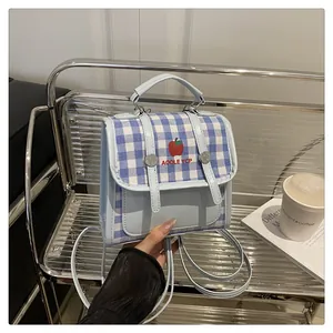 Detail of blue plaid mini backpack with apple logo and strap on silver shelf