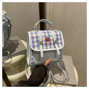 Detail shot of mini blue plaid backpack featuring apple embroidery and leather texture