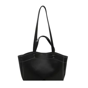 Black leather tote bag with white contrast stitching and double handles on white background