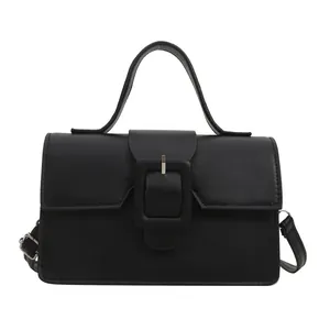 Minimalist matte black leather handbag with large buckle and adjustable strap