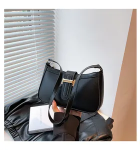 Detail of black leather underarm bag with gold metal buckle and vintage trapezoid design